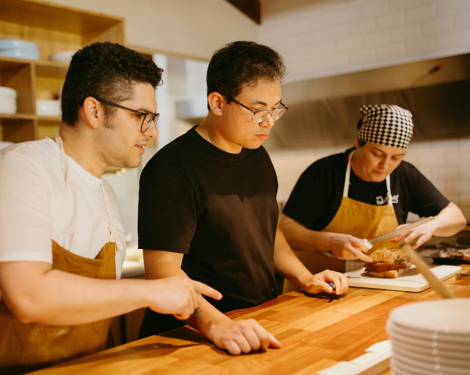 Three chefs working together at a kitchen counter, preparing dishes with focus and teamwork.